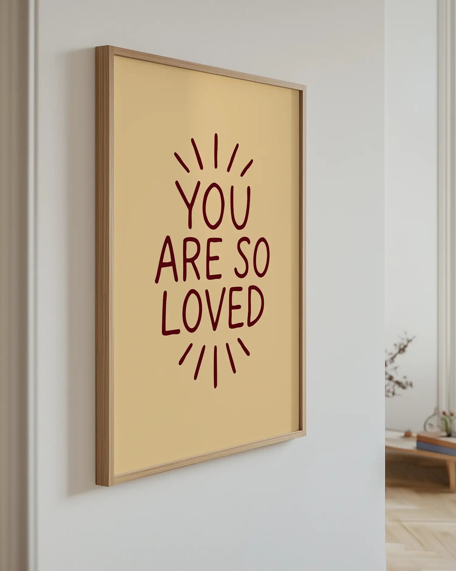 Framed artwork with 'YOU ARE SO LOVED' text on a wall.