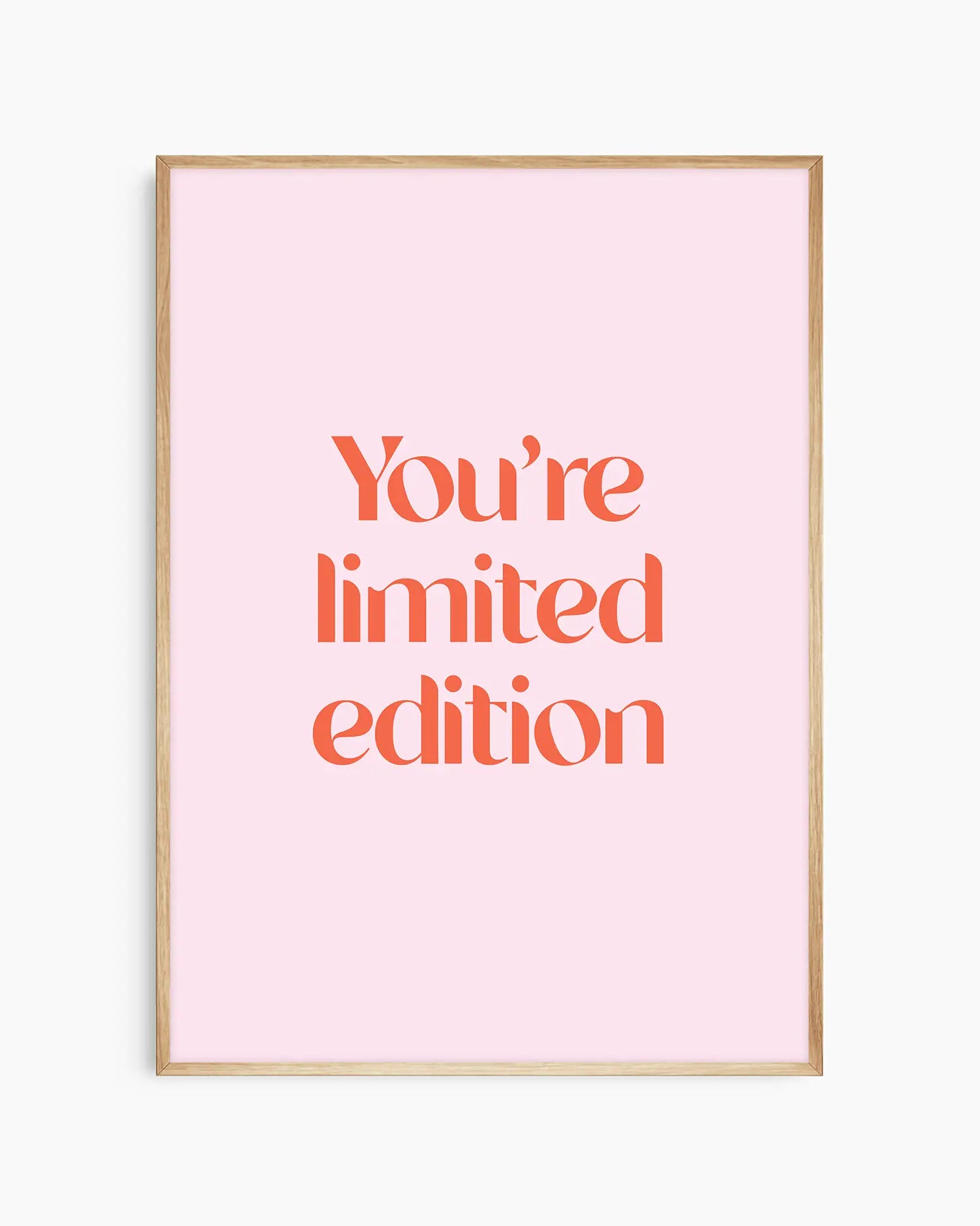 Children's poster with red text 'You're limited edition' on a pink background framed in an oak frame.