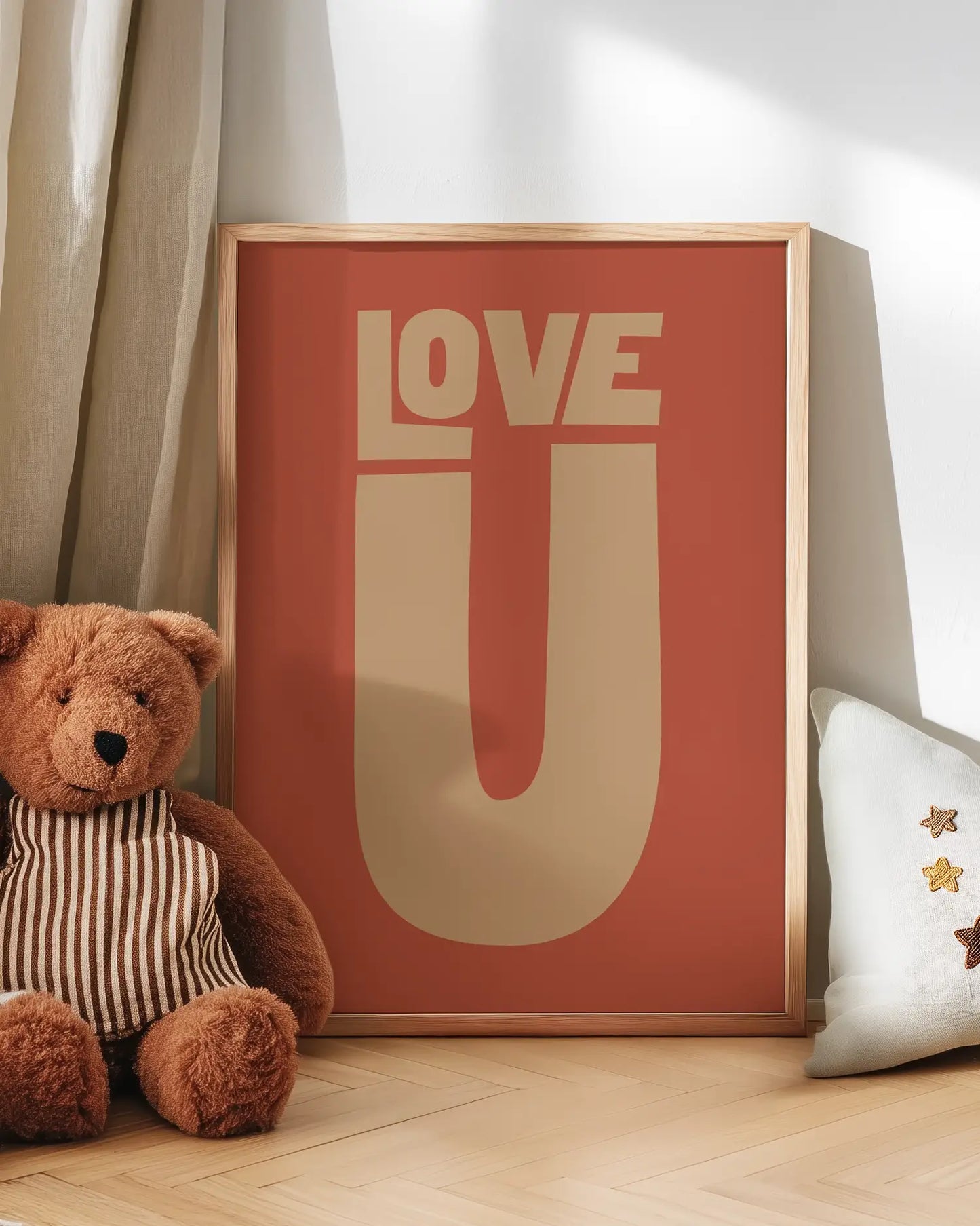 Teddy bear next to a framed poster with 'LOVE U' text on a wooden floor.