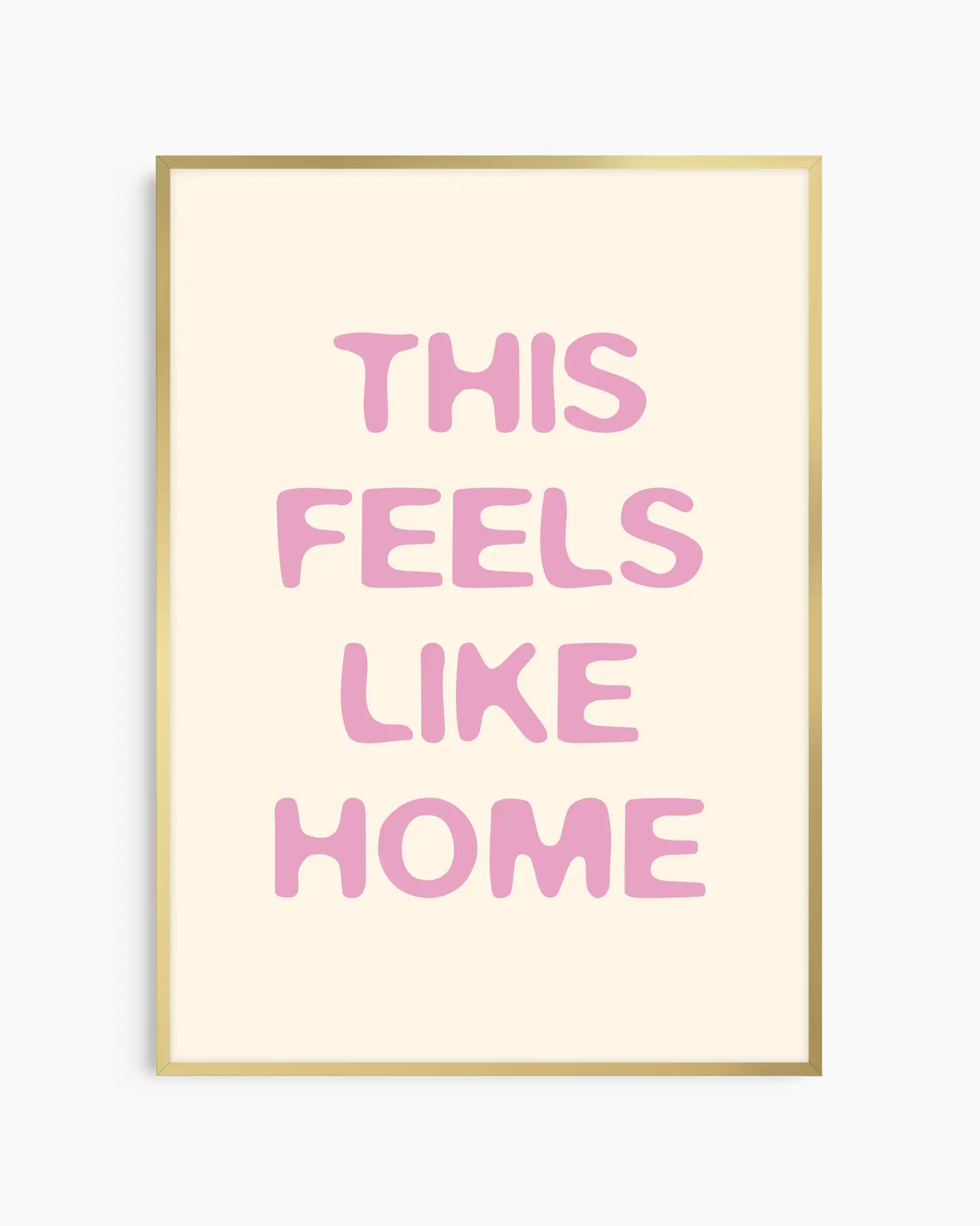 Nursery poster with the text 'This feels like home' written in pink on a beige background, framed in a gold frame