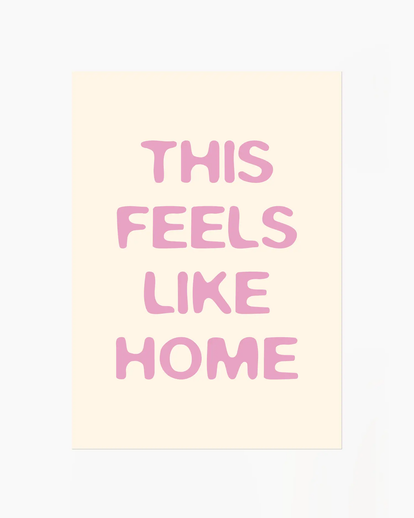 Nursery poster with the text 'This feels like home' written in pink on a beige background