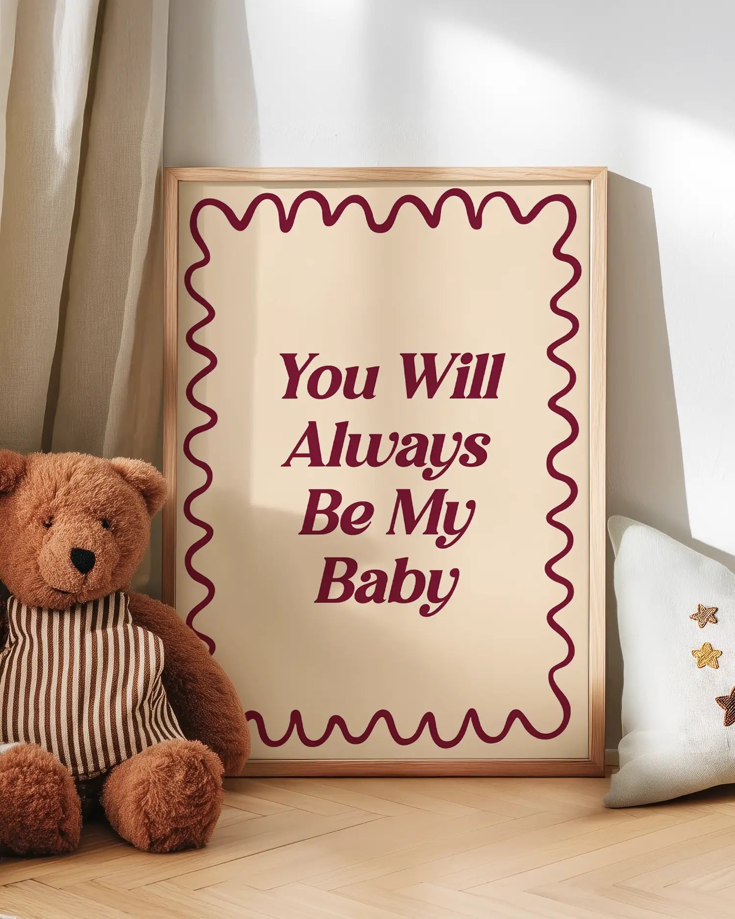 Teddy bear next to a poster with the quote 'You Will Always Be My Baby' on a wooden floor.