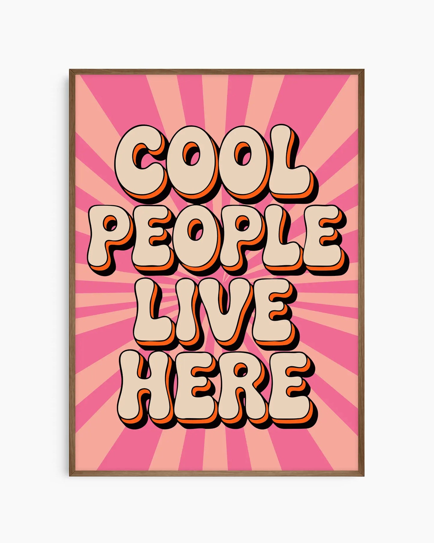 Nursery poster with 'Cool People Live Here' text on a pink sunburst background framed in a smoked oak wooden frame.