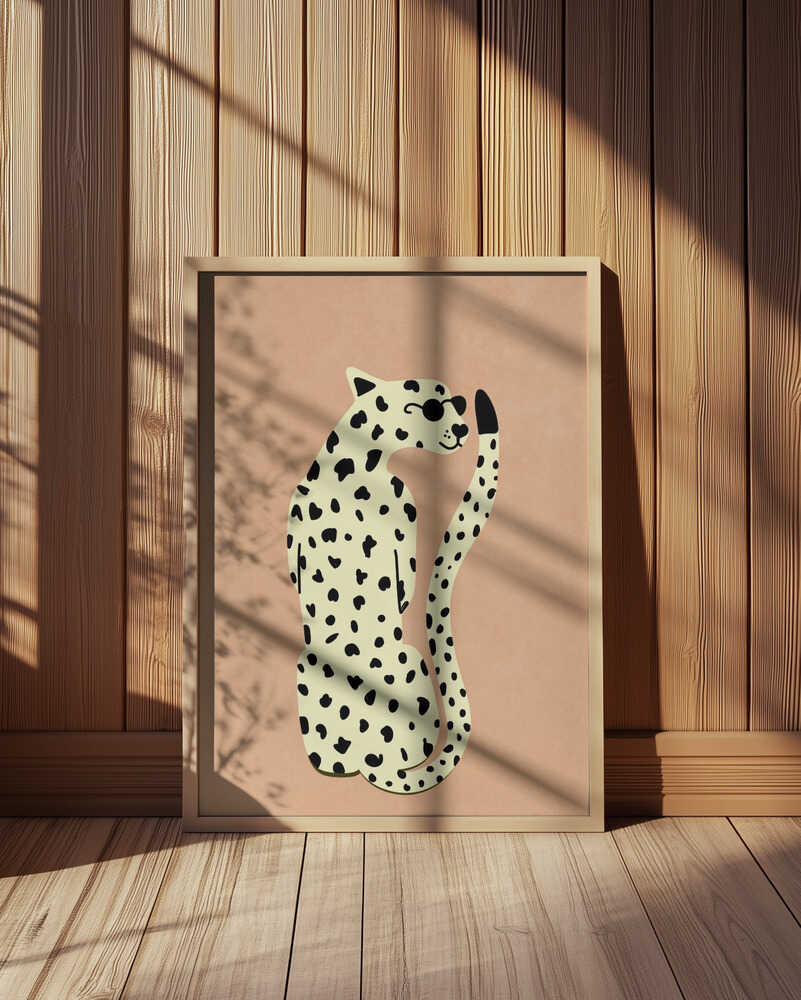 Minimalist poster featuring a stylized leopard in beige and black on a warm sand-colored background. The print is displayed in a light wooden frame, illuminated by soft sunlight and shadows against a wooden wall.