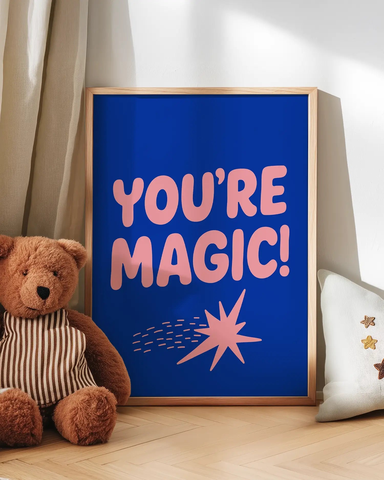 Blue poster with 'You're Magic!' text next to a teddy bear on a wooden floor.
