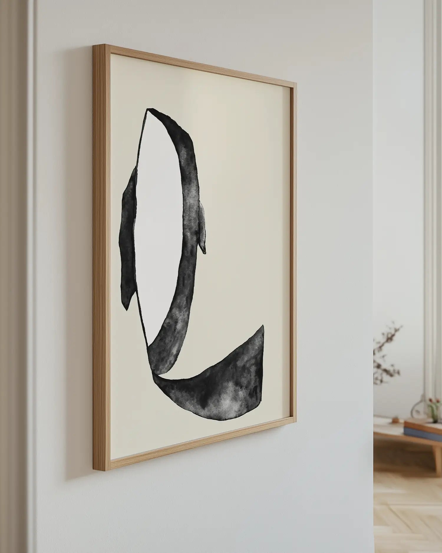 Framed artwork of a killer whale on a wall in a room with a light-colored floor.