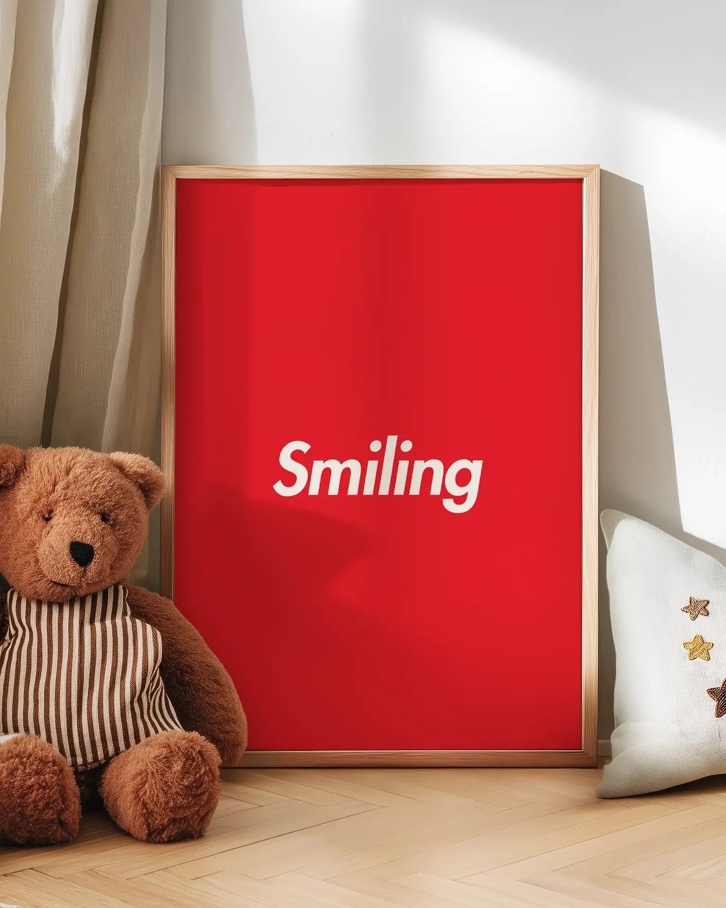 Red poster with 'Smiling' text next to a teddy bear on a wooden floor.