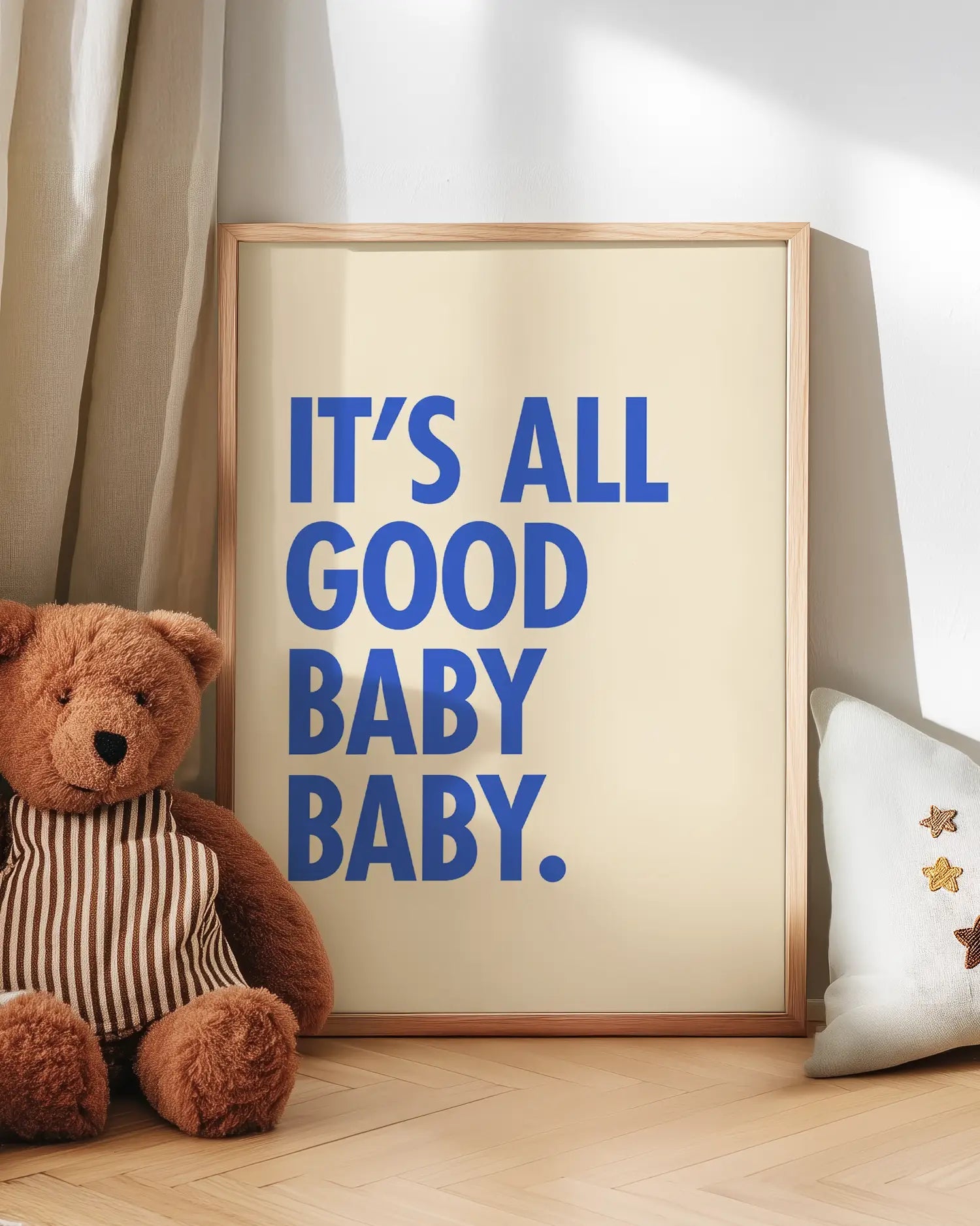 Poster with 'It's All Good Baby Baby' text next to a teddy bear on a wooden floor.