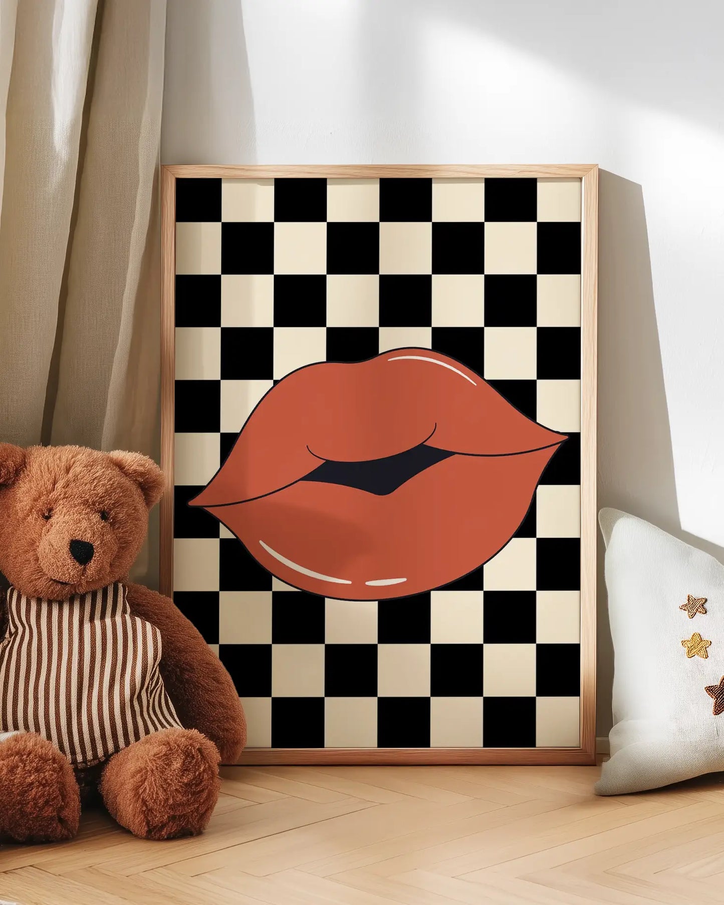 Artwork with checkered pattern and lips next to a teddy bear on a wooden floor.