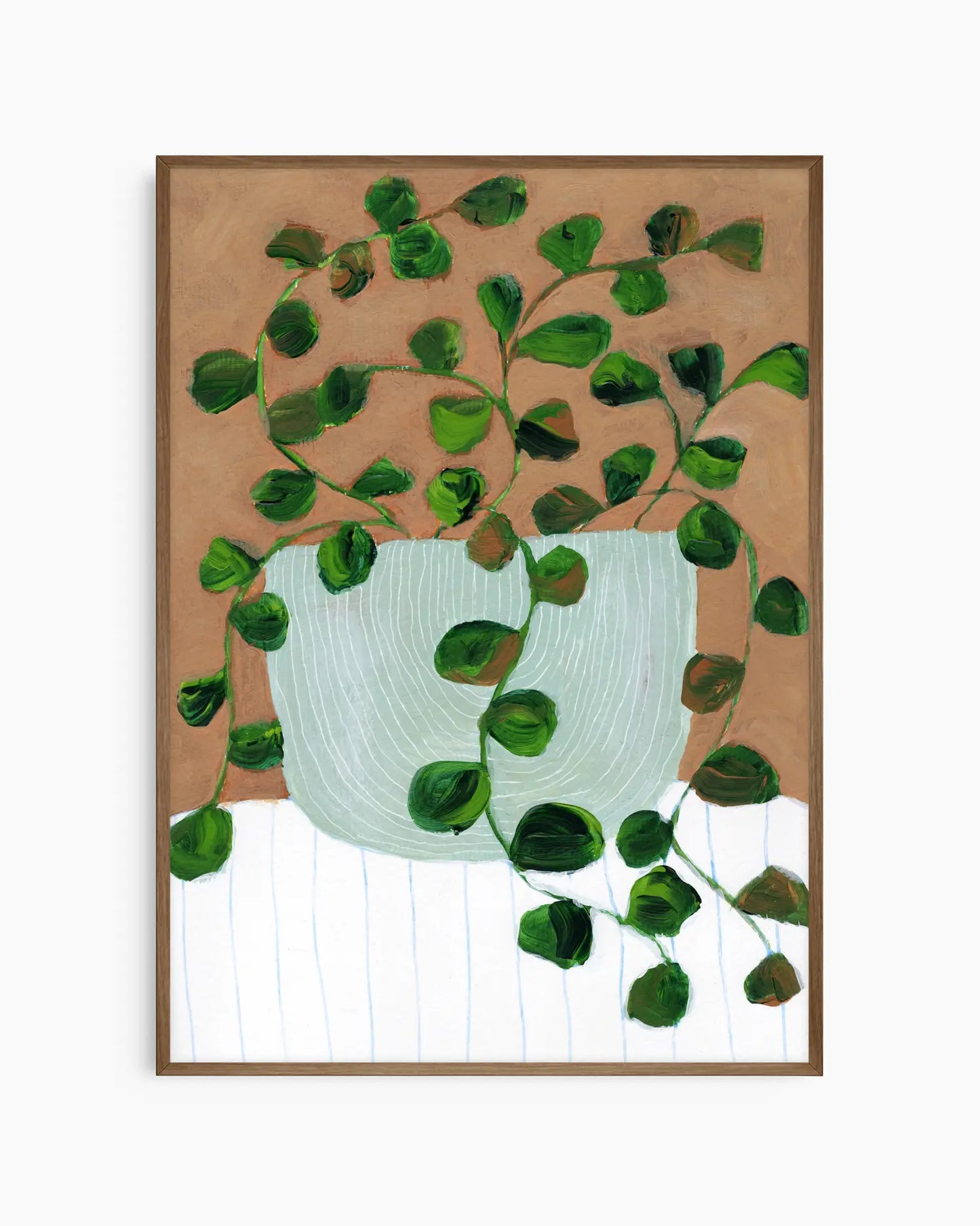 Framed artwork of a green leafy plant in a white pot on a wooden surface.