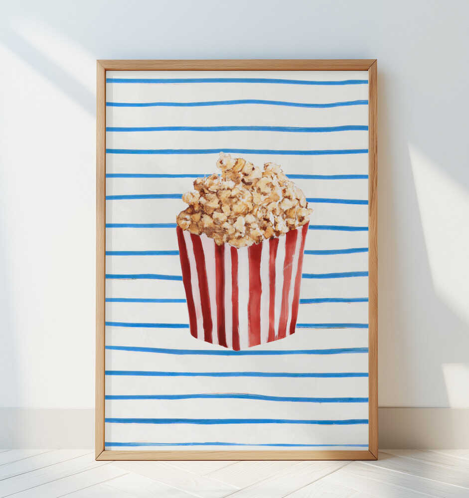 Whimsical popcorn poster in a red-striped box on a lined white background, framed in light wood and leaning against a white wall. Fun and modern kitchen decor or movie night wall art for a cozy, creative home.